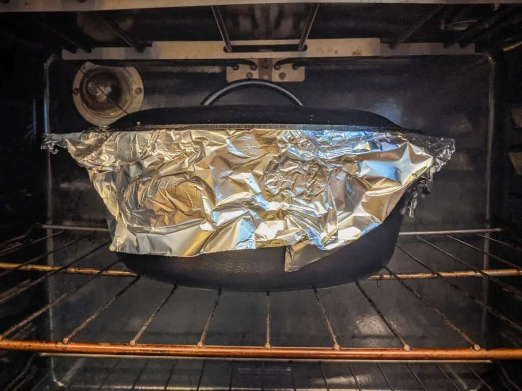Kedjenou cooking in a Dutch oven wrapped in aluminium foil to seal in all of the moisture and flavor.