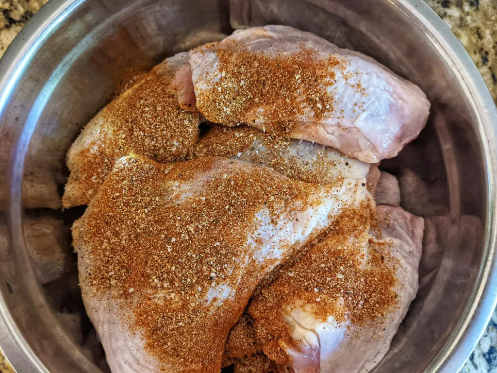 Chicken thighs and legs coated in kedjenou seasoning.