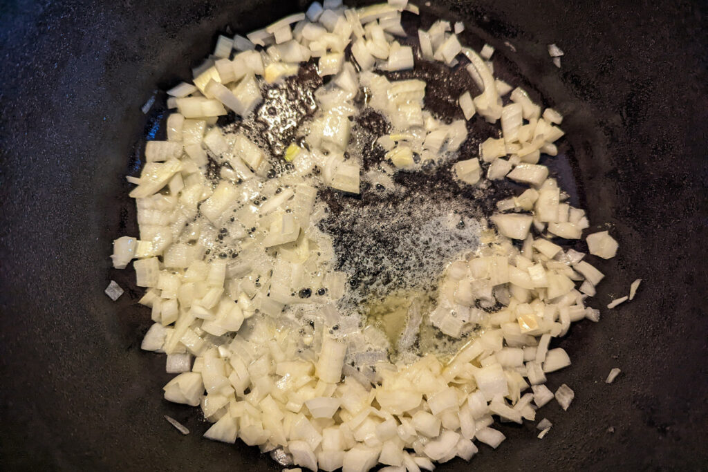 Onions cooking in butter in a dutch oven.