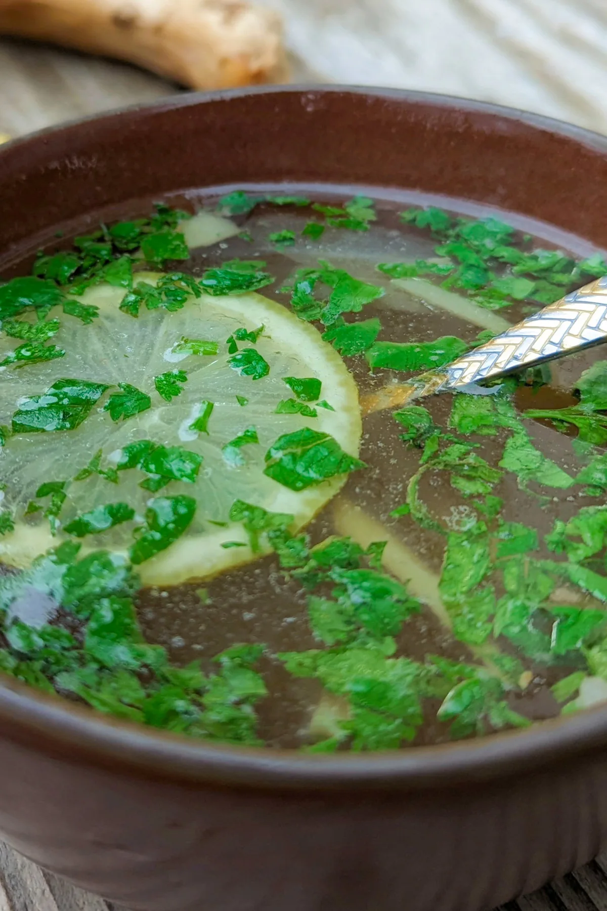 Yakhni in a bowl with lemon and cilantro.