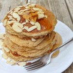 A serving of almond flour pancakes topped with shaved almonds and maple syrup.