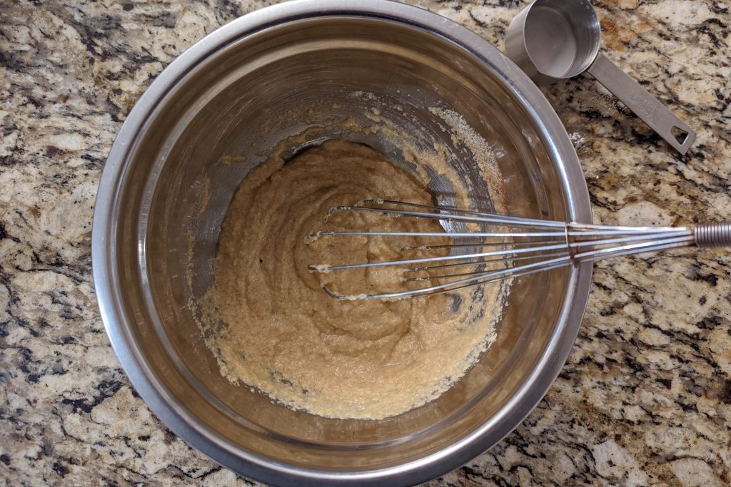 Wet and dry ingredients are mixed in a bowl to form the batter for almond flour pancakes.