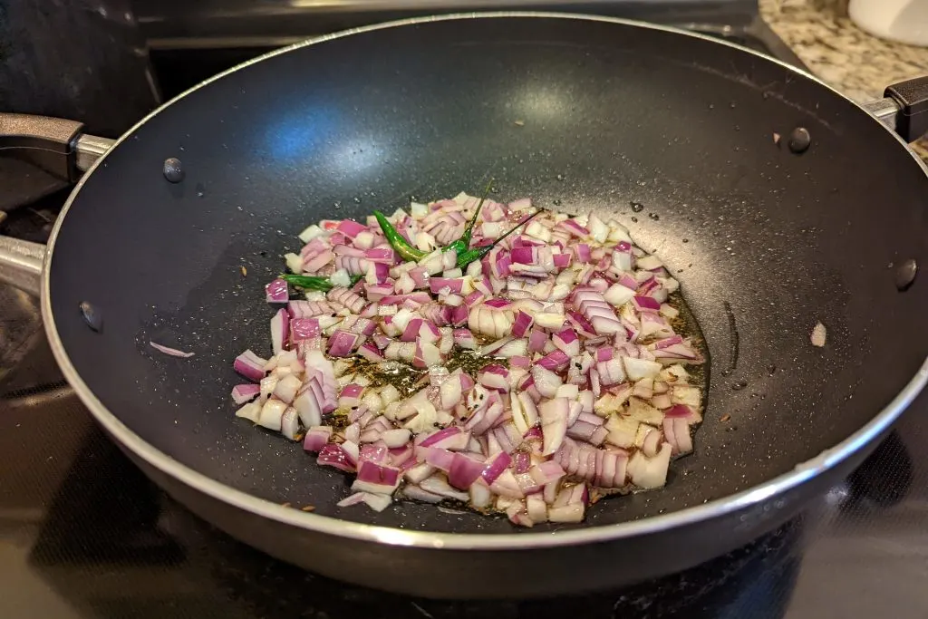 Onions sautéing in a pan with the cumin and chilies.