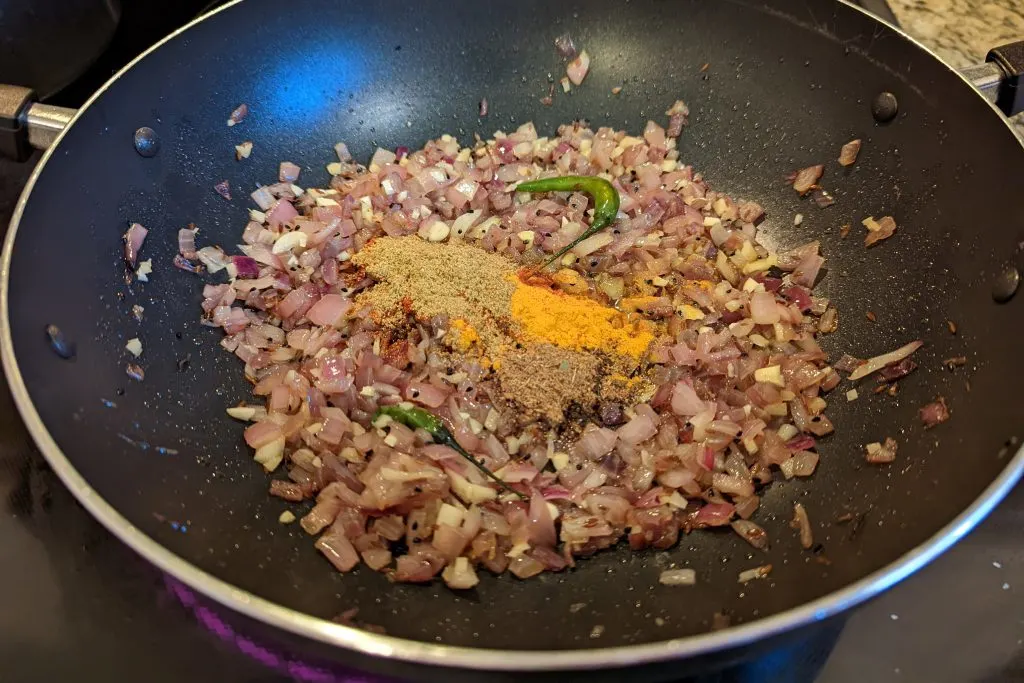 Spices added to the onion mixture cooking in the skillet.