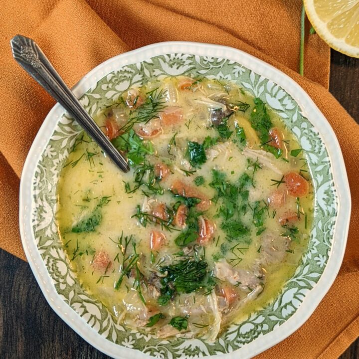 A single serving of chikhirtma garnished with red chili flakes, dill, and cilantro.