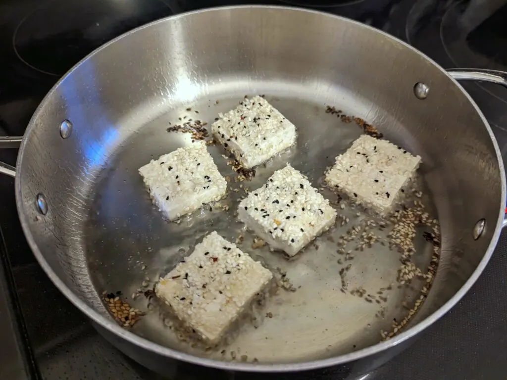 Tofu frying in a pan.