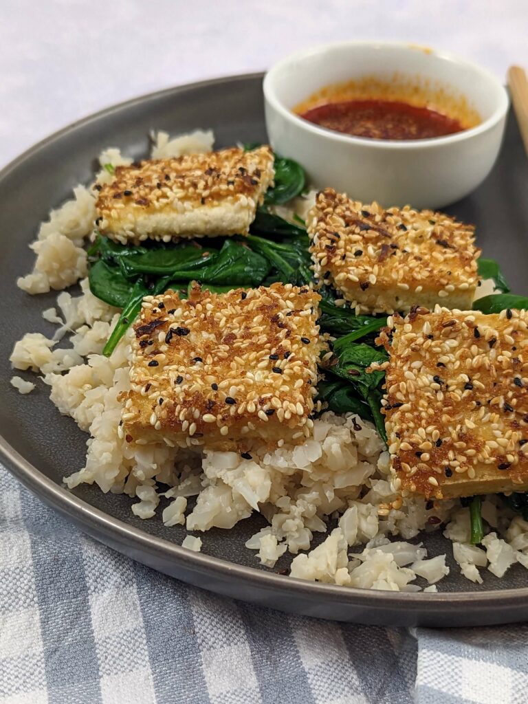 Tofu pieces served on cauliflower rice and cooked spinach.