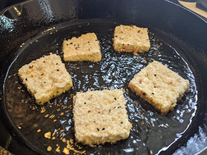 frying the tofu in a cast iron pan