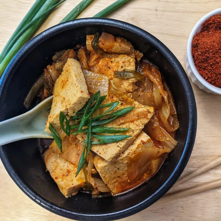 A single serving of kimchi jjigae topped with scallions.