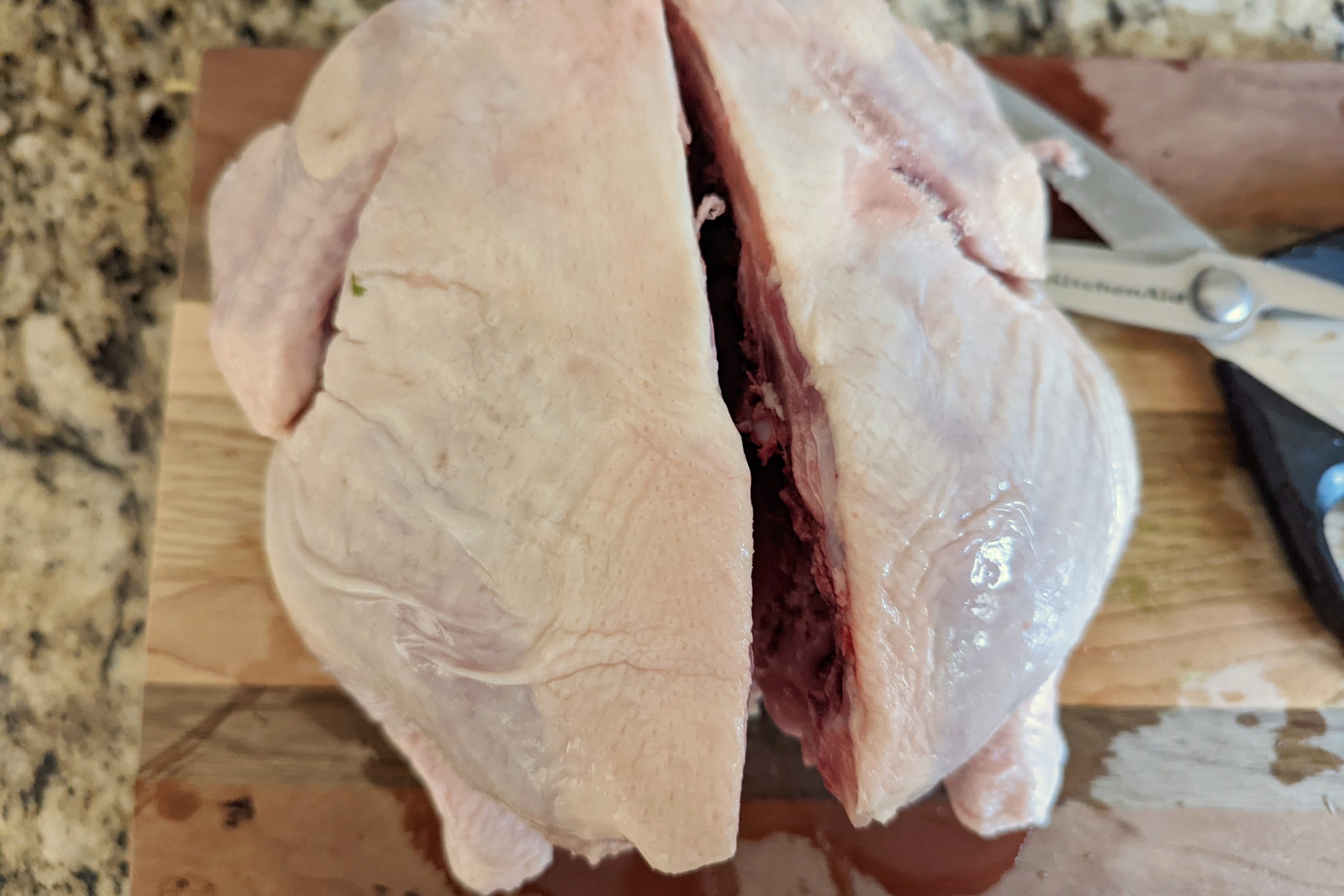 A slit up the spine of the whole raw chicken. 