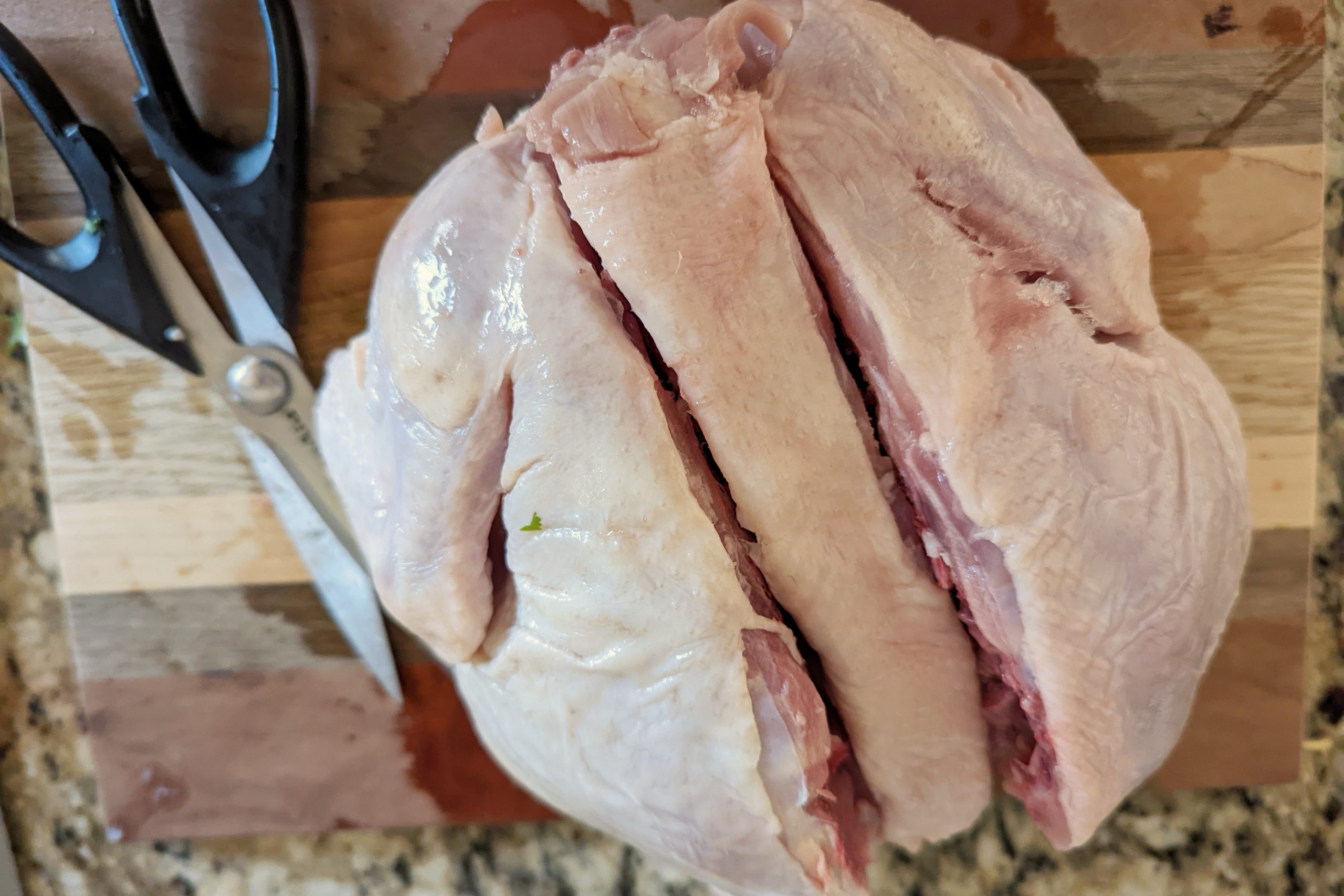 Two slits up the spine of the whole raw chicken. 