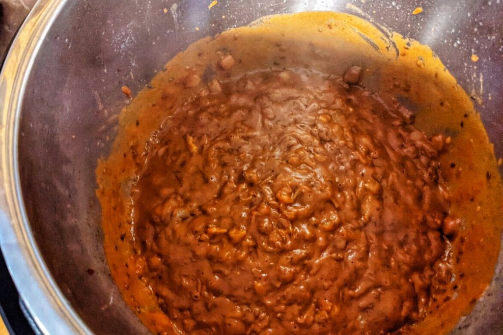 Tomato paste, bouillon, and water are added to the cooked down spiced-onion mixture to create the gravy for Austrian goulash.