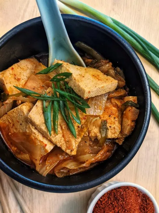 A single serving of vegetarian kimchi jjigae topped with scallions.