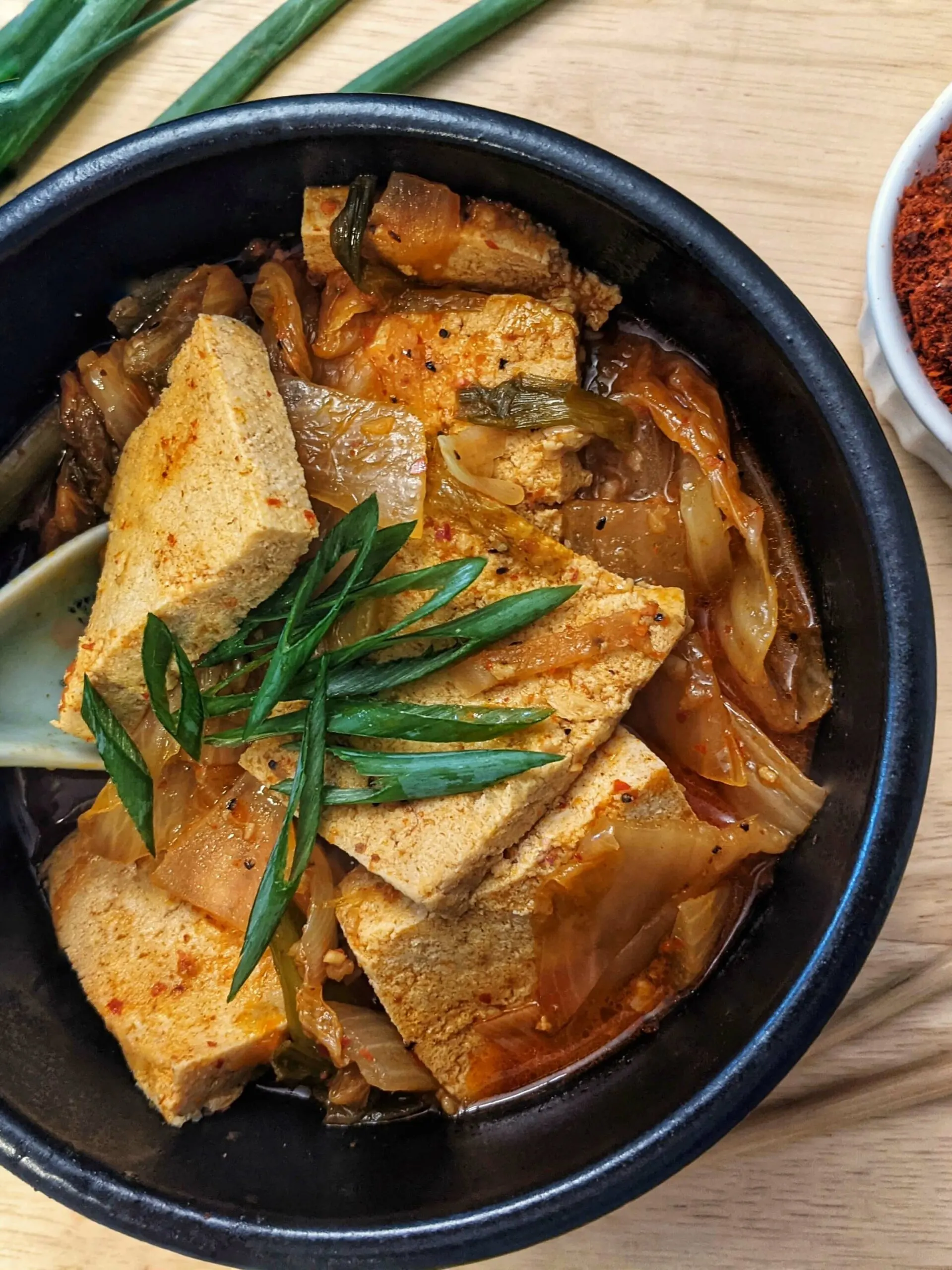 A single serving of vegetarian kimchi jjigae topped with scallions.
