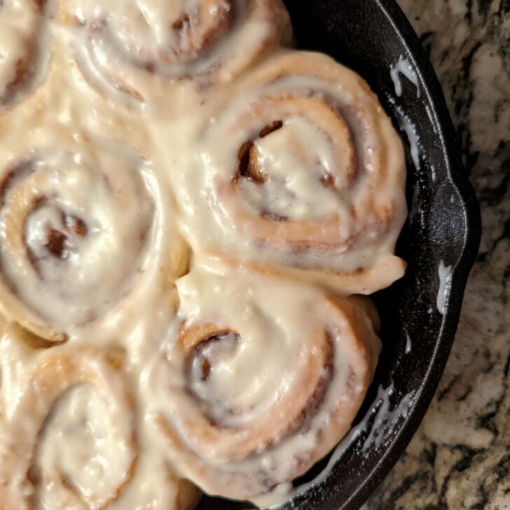 Baked and frosted cinnamon rolls in a cast-iron skillet.