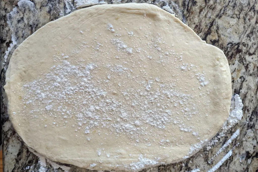 The dough rolled out on a lightly floured surface and sprinkled with flour.