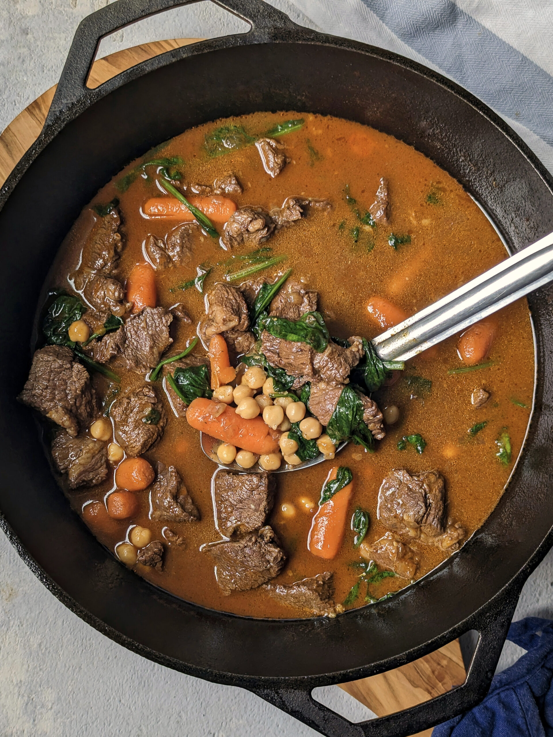Beef and chickpea stew in a Dutch oven with a spoon in it.