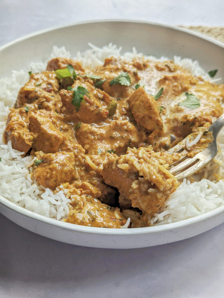 Butter chicken masala over basmati rice and garnished with chopped cilantro.