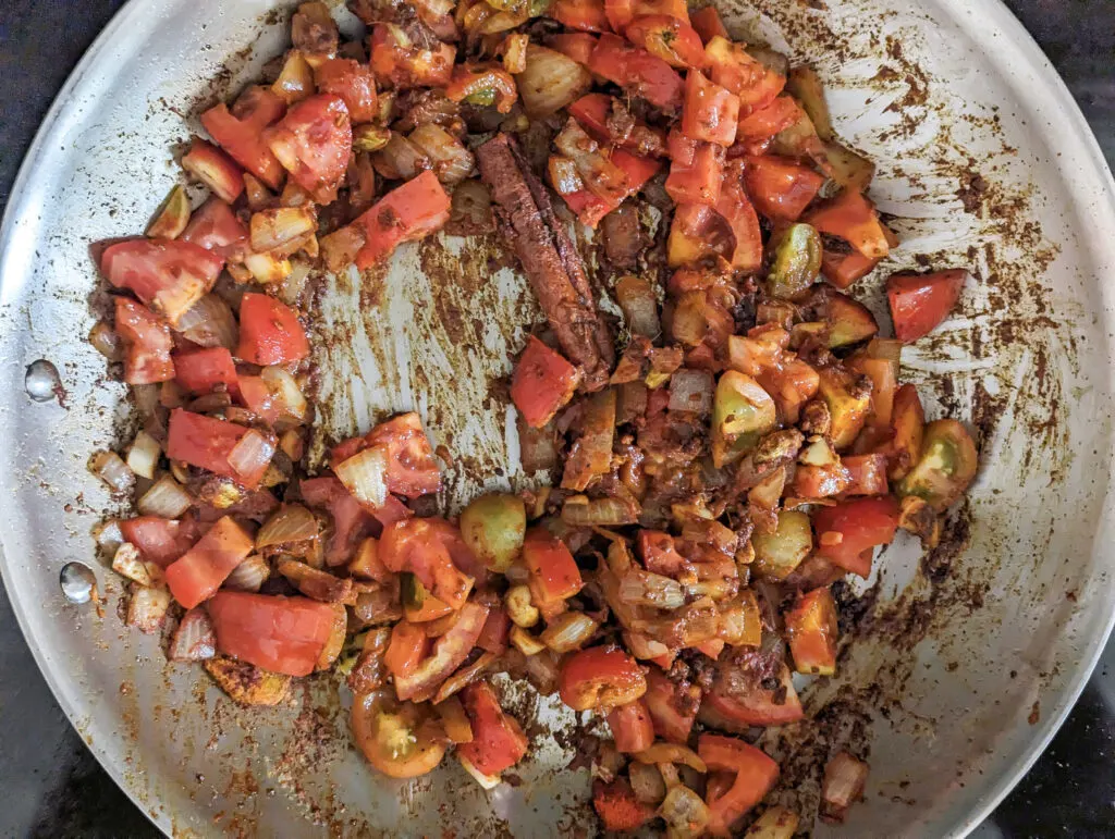 Add tomatoes to the onions and spices.
