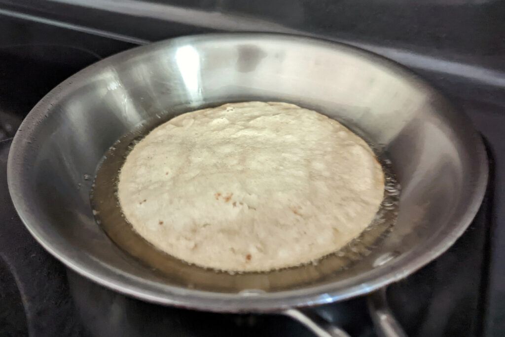 A corn tortilla searing in a pan.