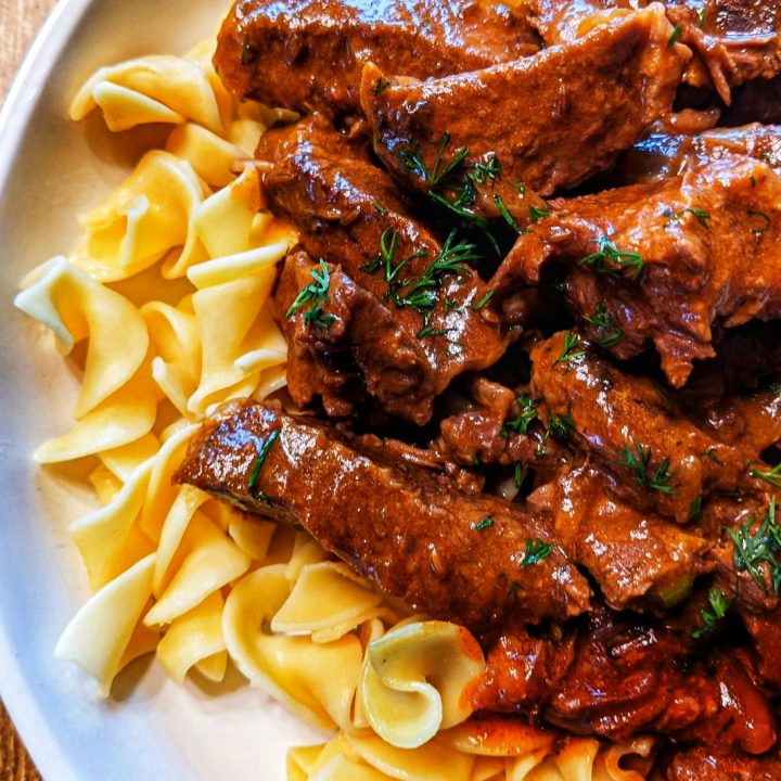 A single serving of Austrian beef stew over buttery egg noodles.