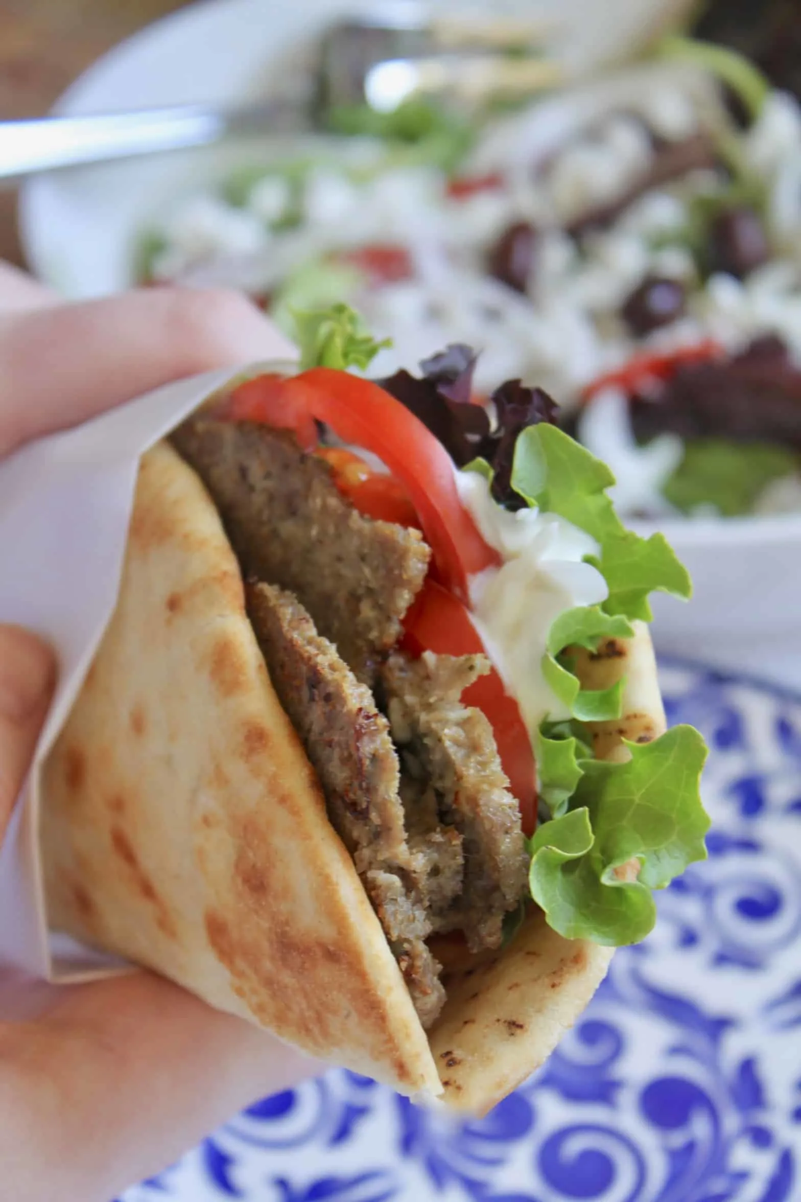 The opening of a greek gyro stuffed with tomatoes, lettuce, and onion.