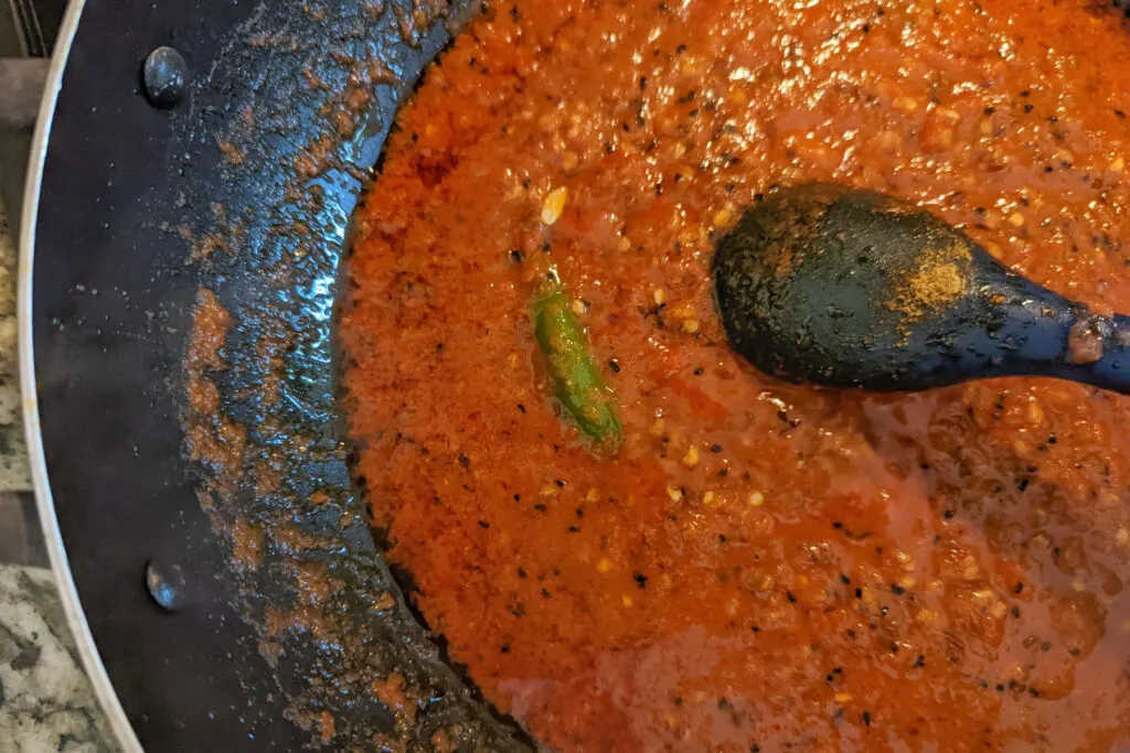 Tomato curry simmering in a pan.
