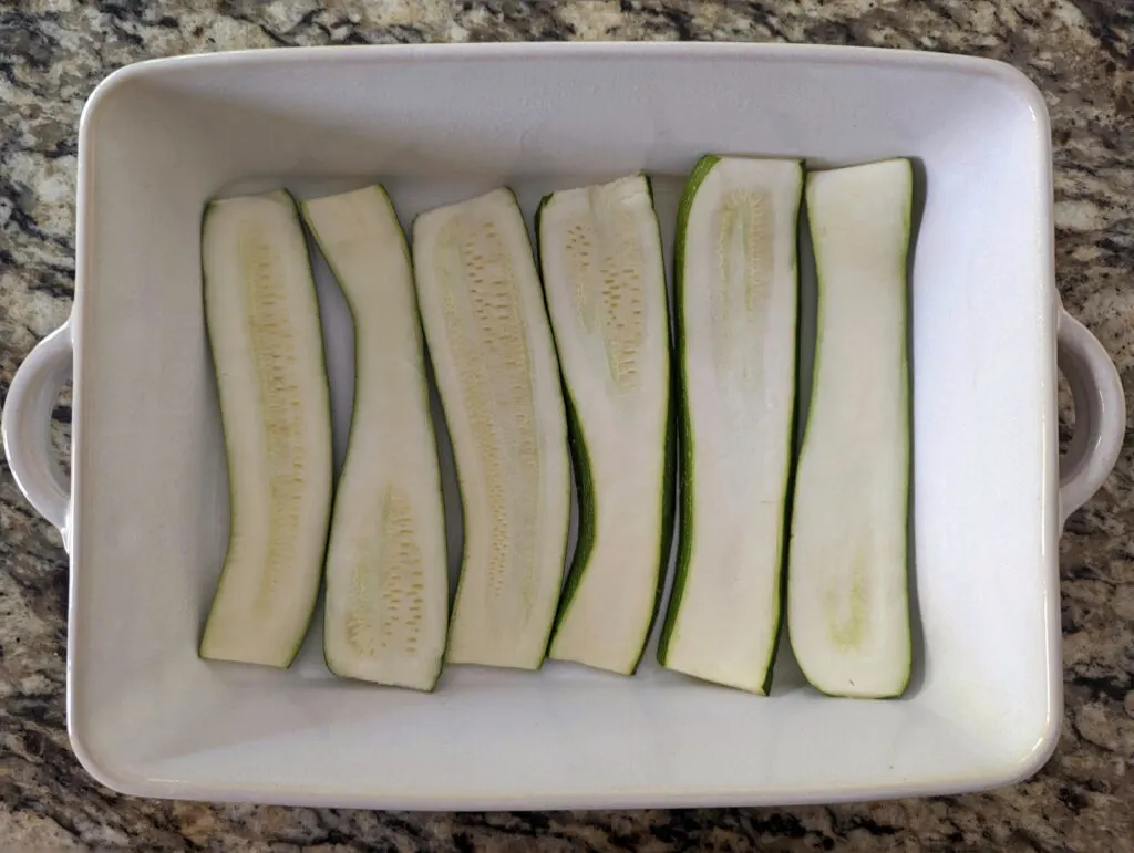 A layer of zucchini strips in a baking dish.