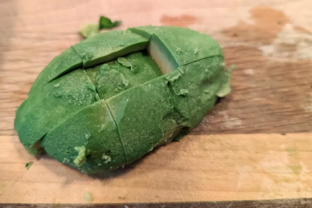 Avocado cut into cubes on a cutting board.
