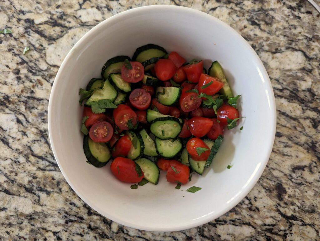 Cucumber, tomatoes, and cilantro in a small bowl.