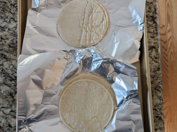 Line foil onto a rimmed baking sheet and set the corn tortillas onto it