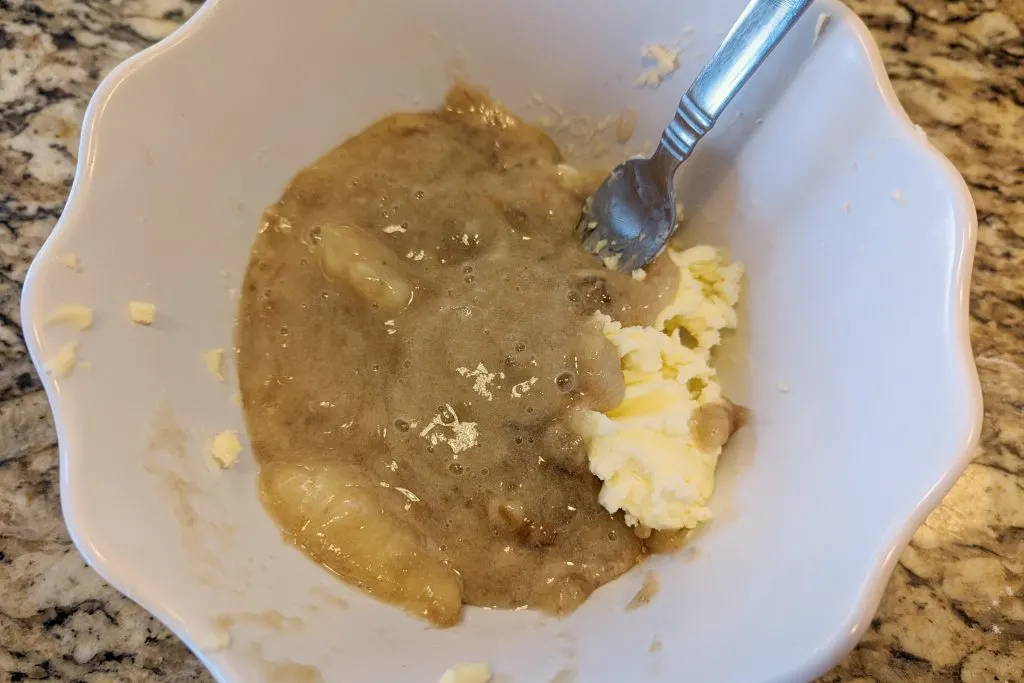 Mushed banana and butter in a mixing bowl.