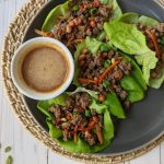 Beef lettuce wraps garnished with scallions, peanuts, and Sriracha.