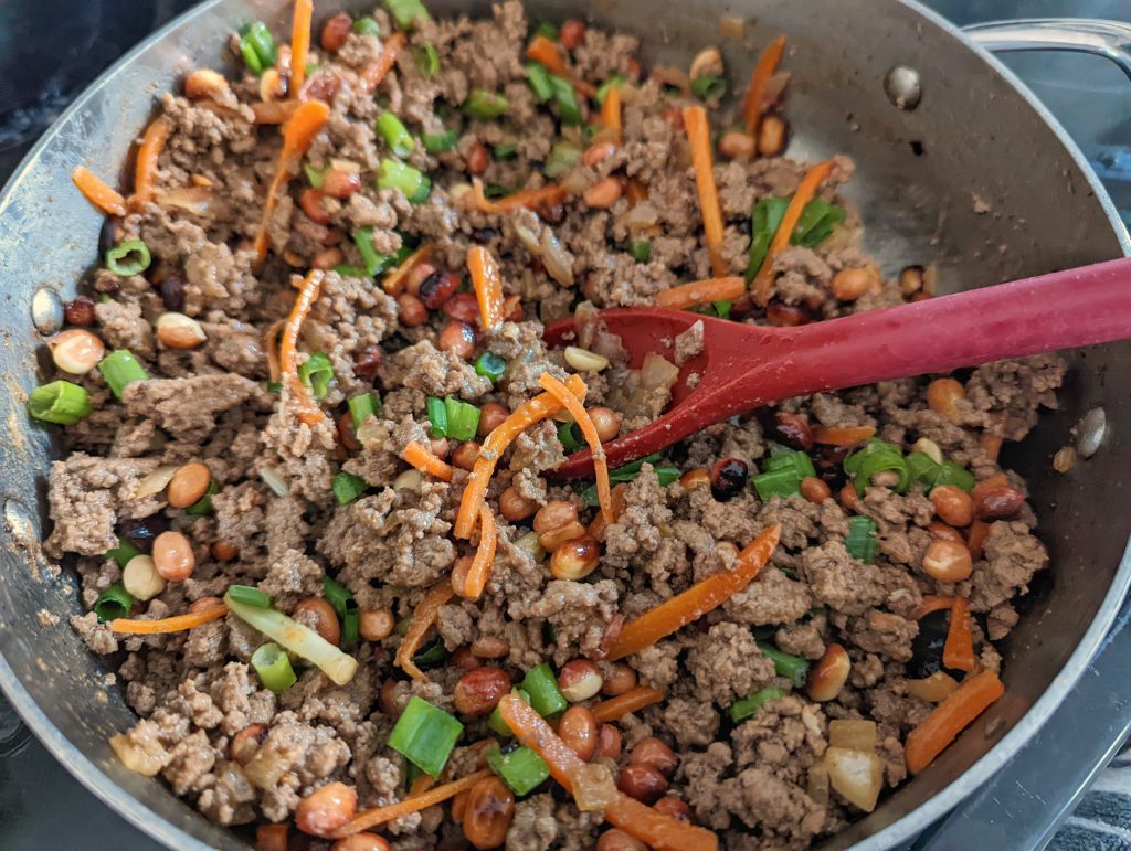 Beef and vegetables searing in a saute pan.