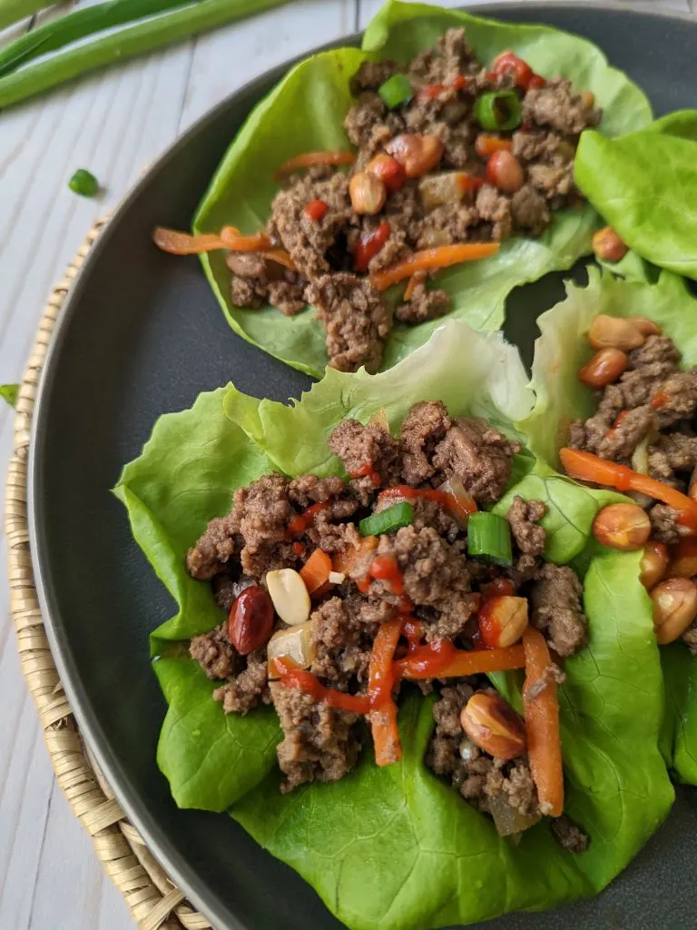 Beef lettuce wraps on a plate and garnished with peanuts. 