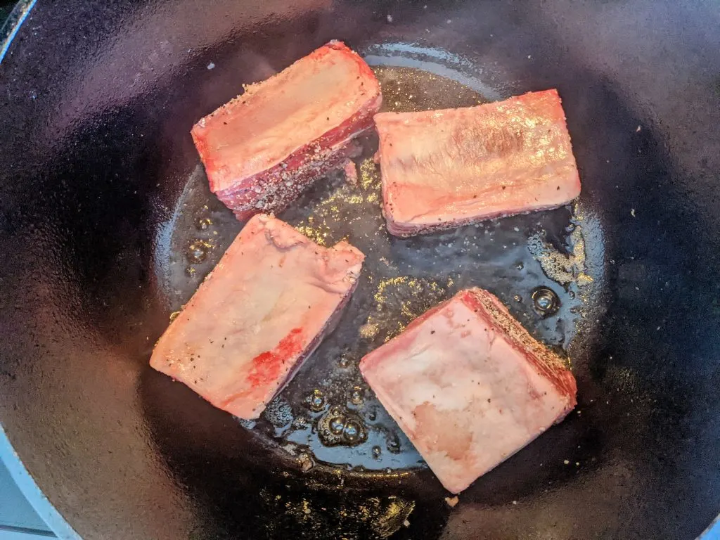 Short ribs searing in a dutch oven.
