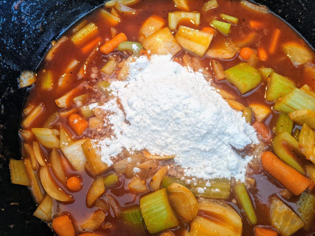 Flour is added to the vegetables to form a roux for braised short ribs.