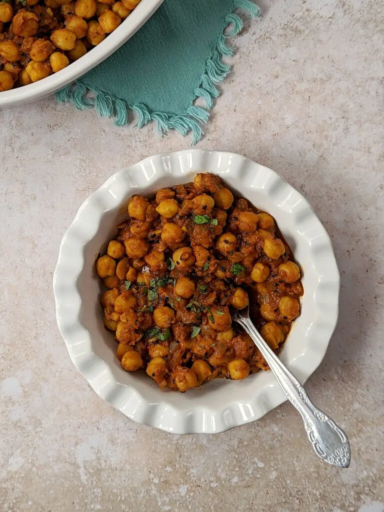 Channa Masala in a serving bowl topped with chopped cilantro.