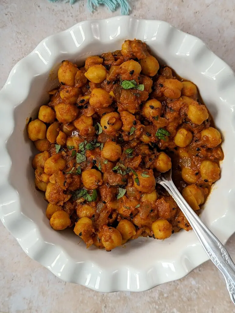 Chana Masala in a serving bowl topped with chopped cilantro.