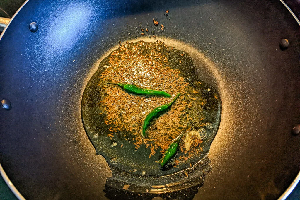 Chilies and cumin seed cooking in oil.