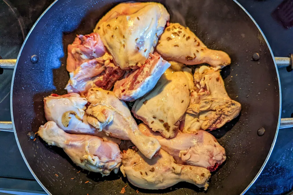 Fry the chicken pieces in ghee and cumin seeds.