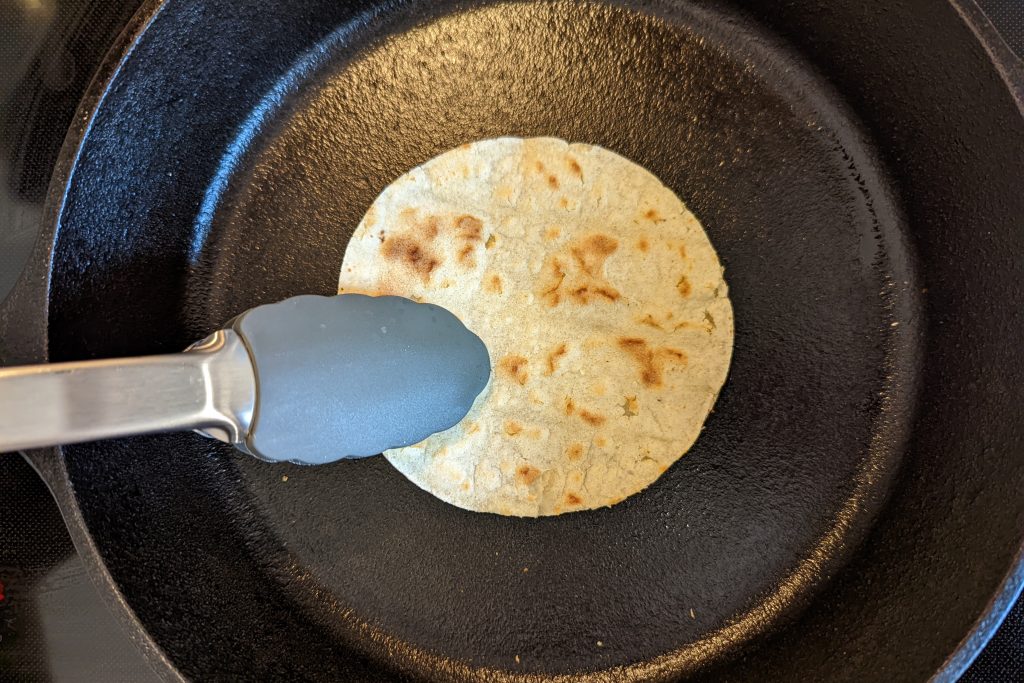How to prepare a corn tortillas: flip and heat the other side of the tortilla until brown spots begin to appear.