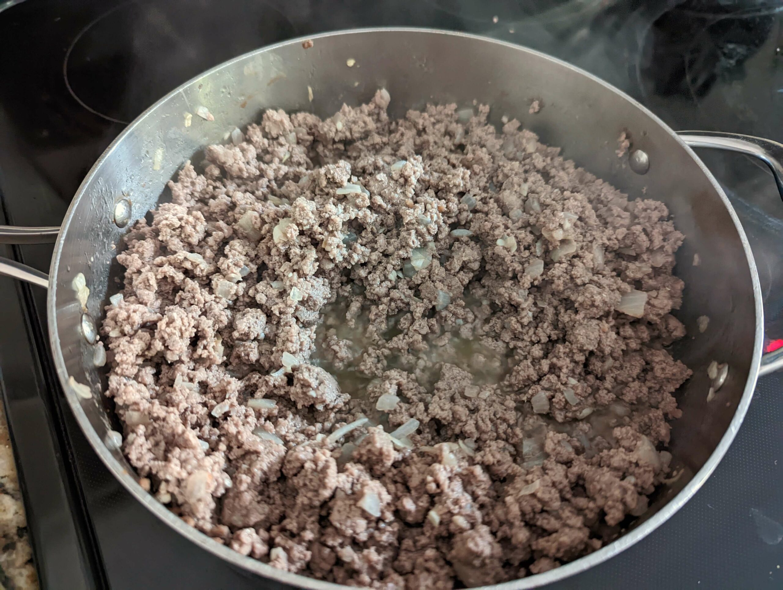Ground beef cooking with onions in a pan.
