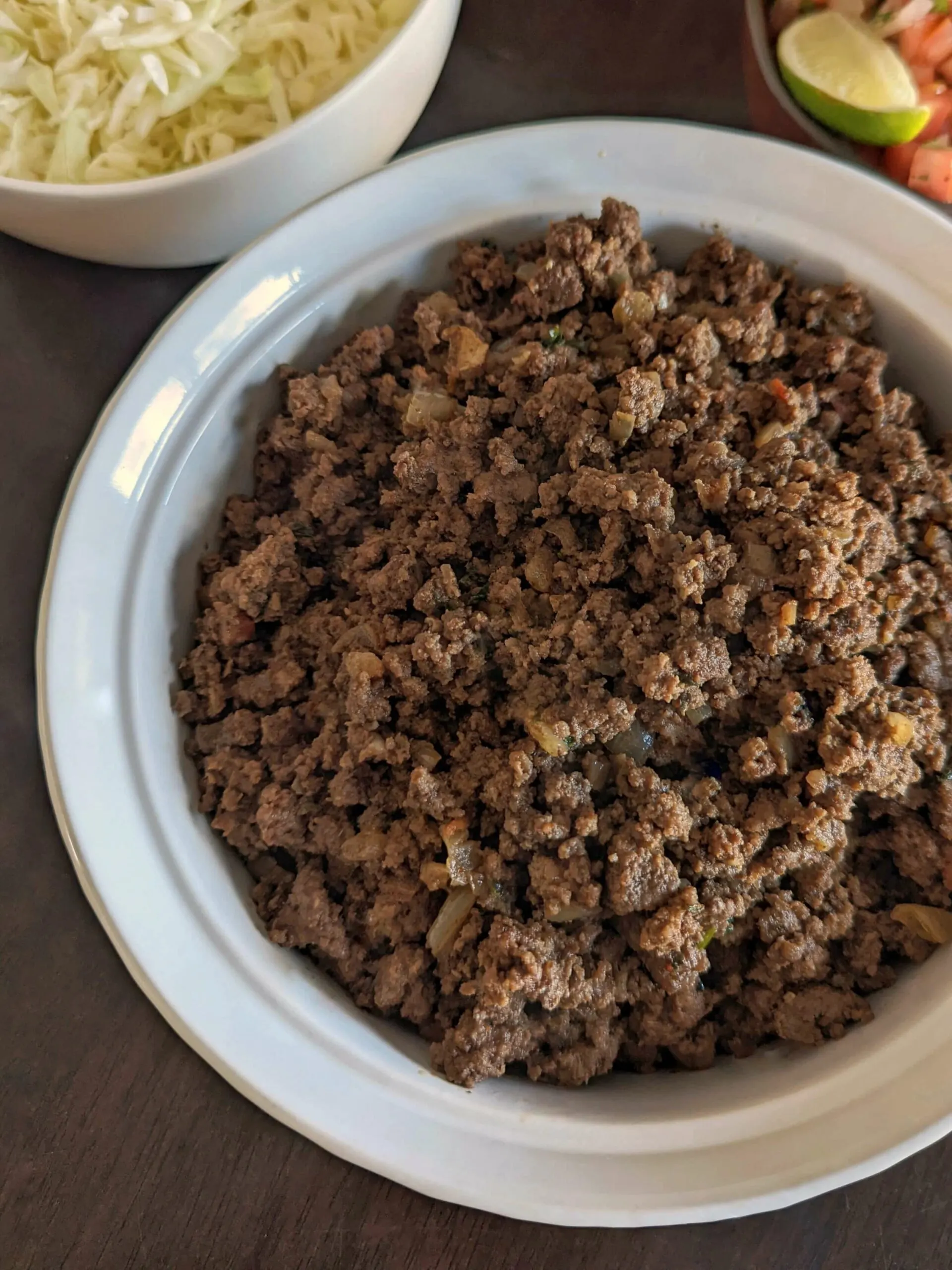 A taco bar with a serving of ground beef in the center.