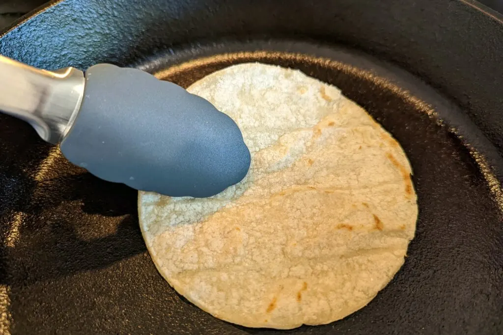 A dry corn tortilla warming in a pan.