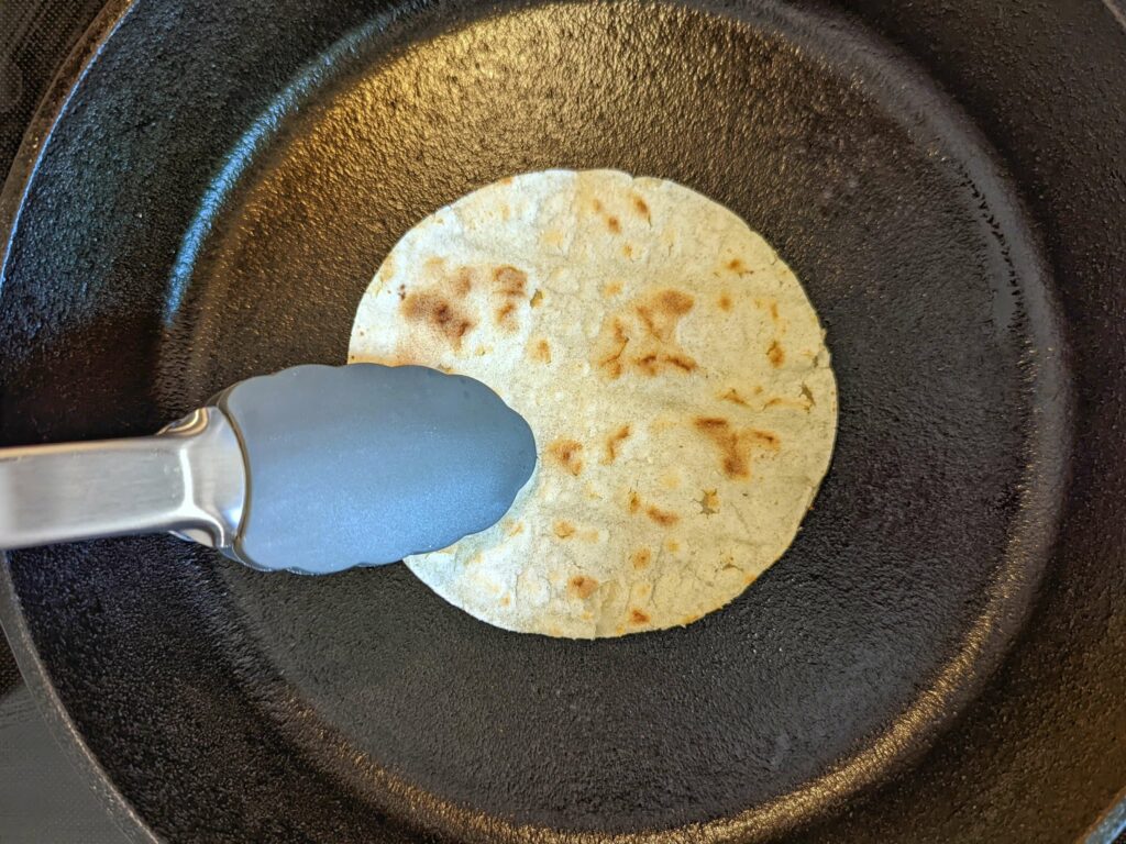 A dry corn tortilla warming in a pan.