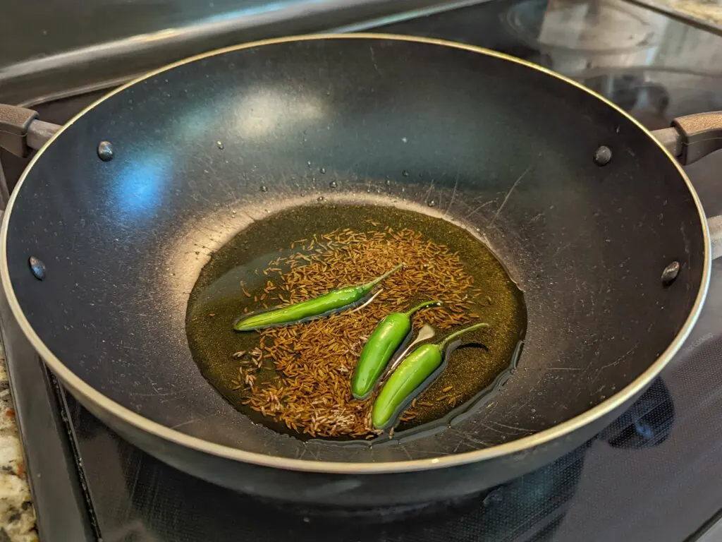 Cumin seeds and chilies toasting in oil.