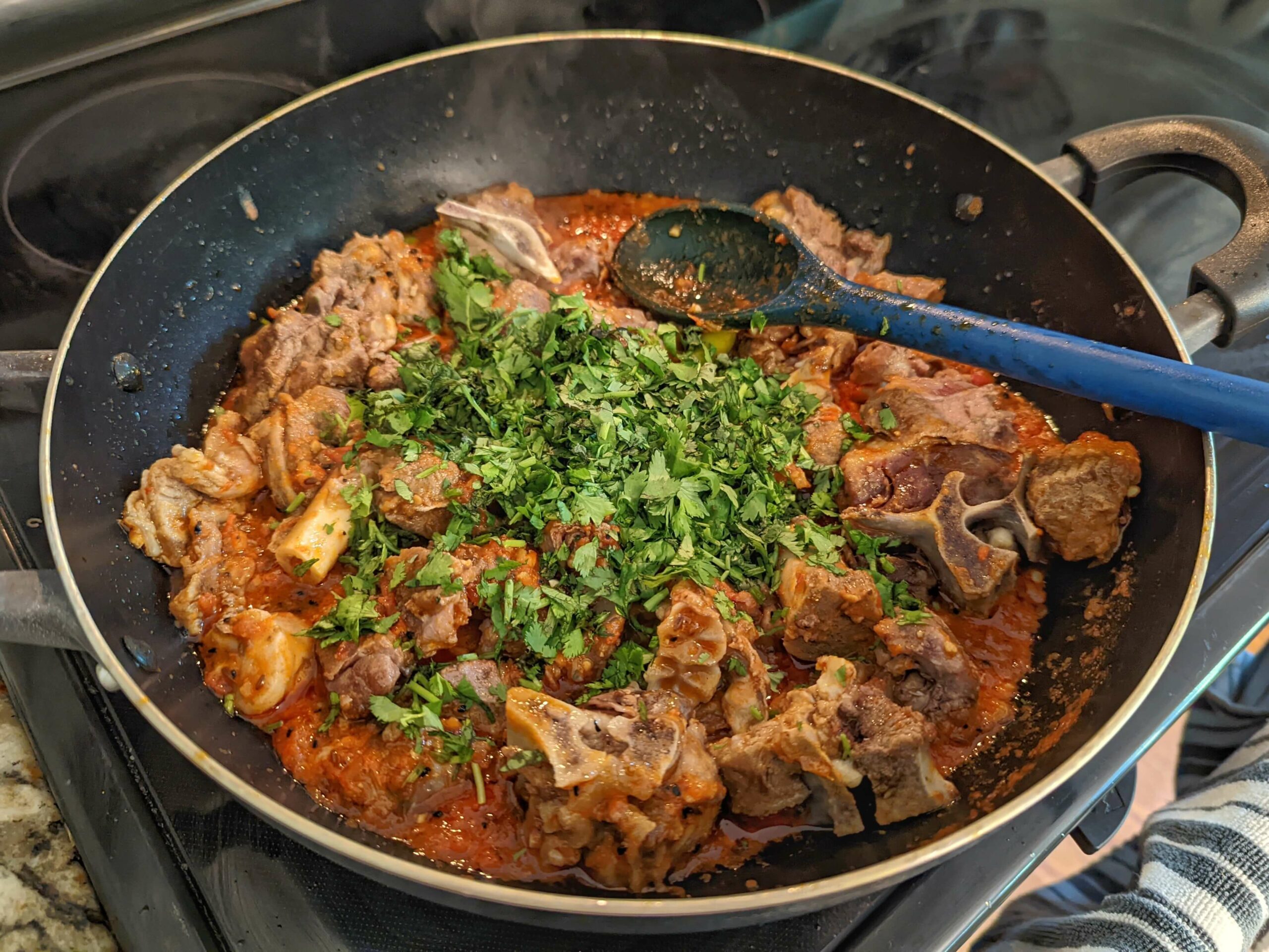 Add the pressure-cooked goat meat to the masala and add cilantro.