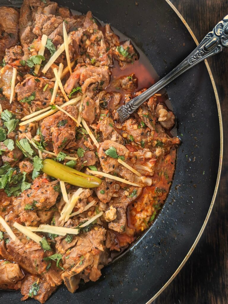 Karahi gosht in a karahi and topped with fresh cilantro and ginger.