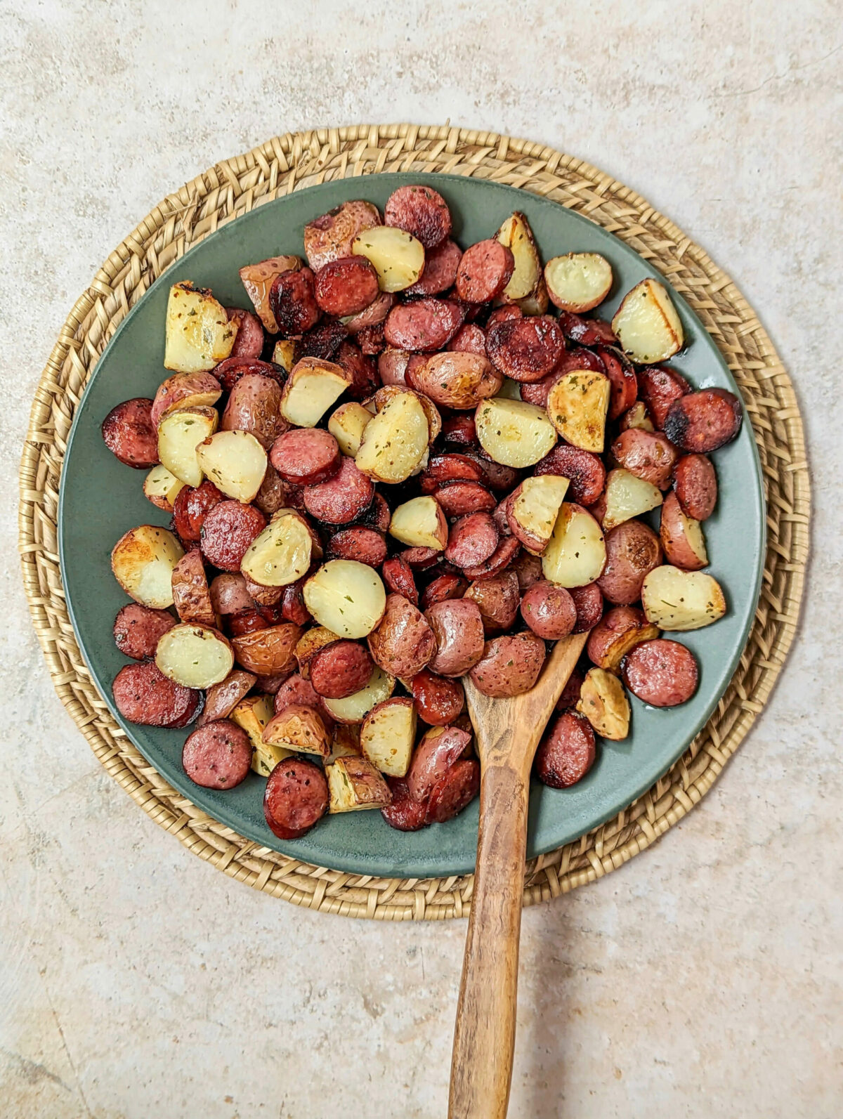 Kielbasa and potatoes on a plate with a serving spoon.